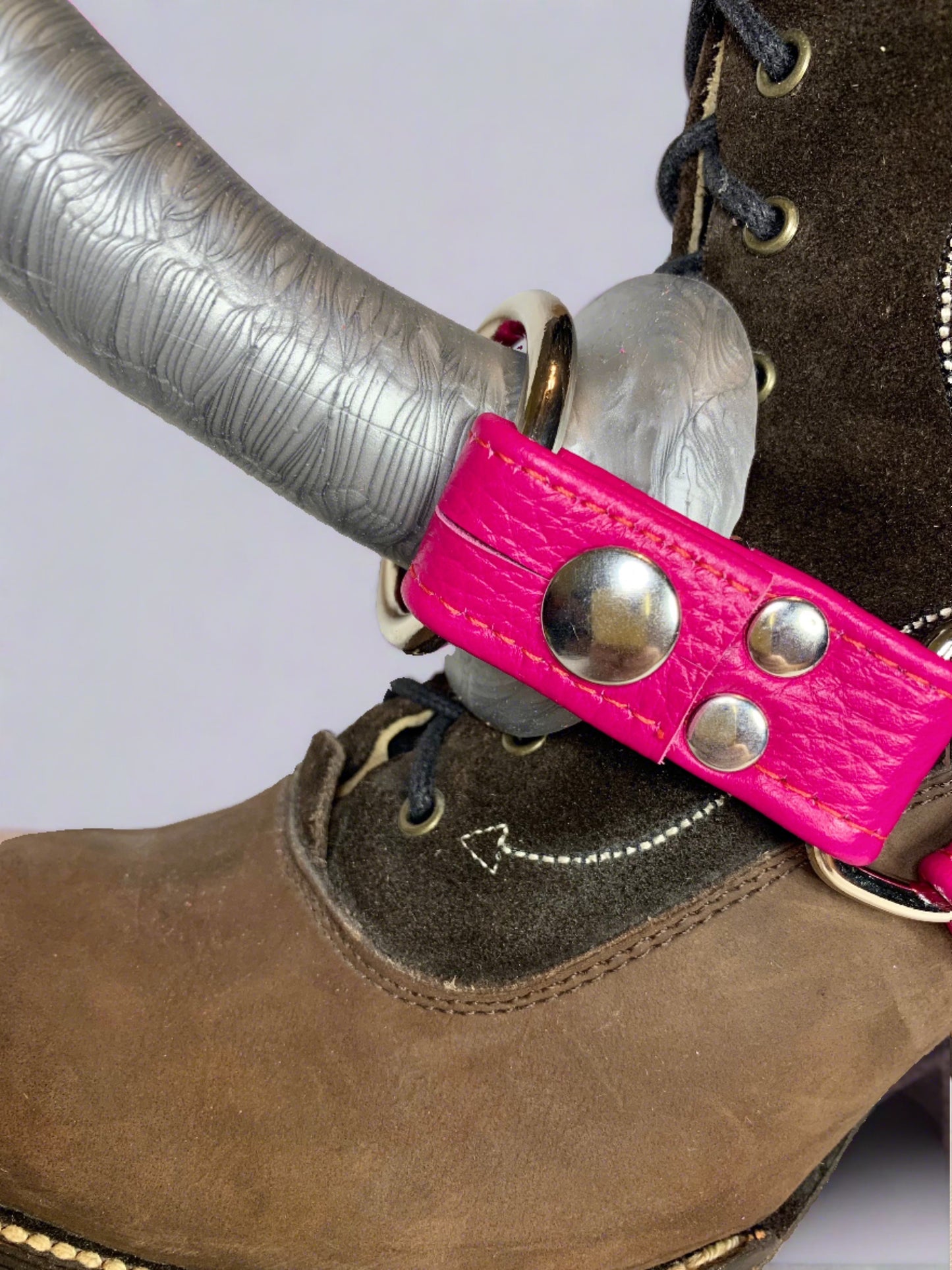 brown suede boot with a magenta leather boot strapon harness and a silver dildo