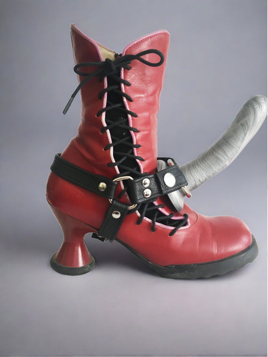 Red leather boot with a side lace up, wearing a black leather boot strapon harness
